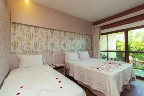 two beds in a room with roses on the covers at Pedra do Sino Hotel in Piranhas