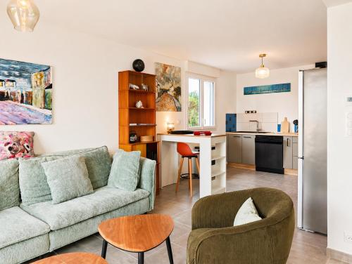 a living room with a couch and chairs and a kitchen at La Maison des Falaises in Crozon