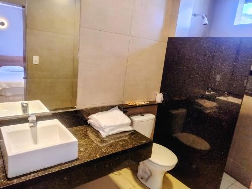a bathroom with a sink and a toilet and a mirror at Real Hotel in Juiz de Fora
