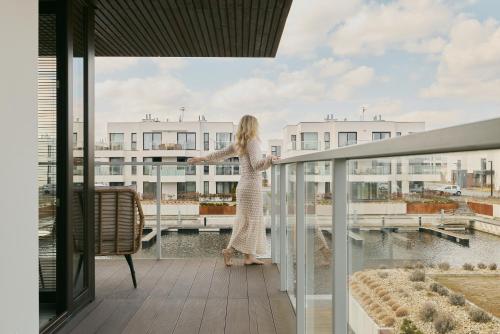 a woman standing on a balcony looking out at the water at Sol Marina Riverview with free Parking & SPA additional by Downtown Apartments in Wiślinka