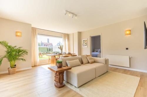 a living room with a white couch and a table at Casiola - Charming Apartment with Garden & Parking in Cadzand