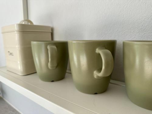 three coffee mugs sitting on a shelf at Cliff House, Azores splendid Ocean View in Horta