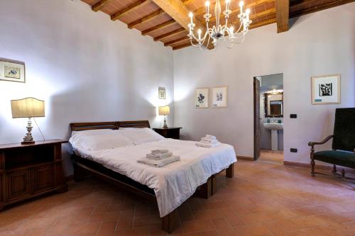 a bedroom with a bed and a chair and a chandelier at Agriturismo Le Mortinete in L'Ugolino