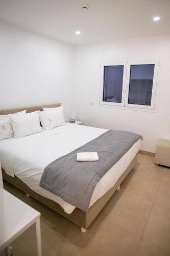 a white bedroom with a large bed and two windows at Casa da Pegada in Macedo de Cavaleiros