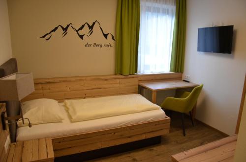a bedroom with a bed and a desk and a television at Wildwiesenhof in Miesenbach