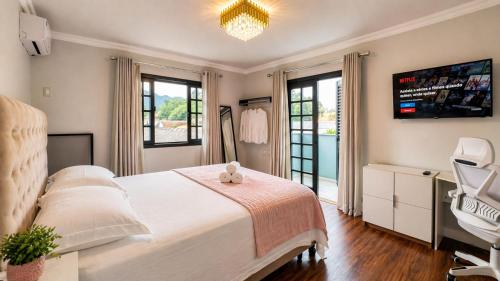 a bedroom with a white bed and a dresser and windows at Casa Premium no Centro - Passos do Alles Park in Pomerode