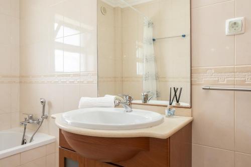 a white bathroom with a sink and a tub at Montesol by ALGARVEMANTA in Manta Rota
