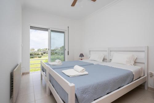 a white bedroom with a large bed and a window at Montesol by ALGARVEMANTA in Manta Rota
