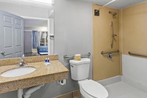 a bathroom with a toilet and a sink and a mirror at Rodeway Inn Owensboro South in Owensboro