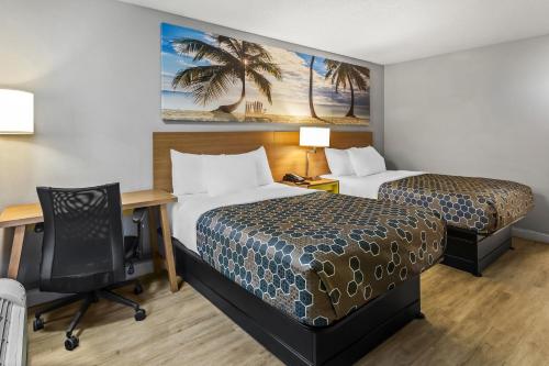 a hotel room with two beds and a desk at Rodeway Inn Owensboro South in Owensboro