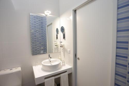 uma casa de banho branca com um lavatório e um espelho em daPraça Apartments no Porto