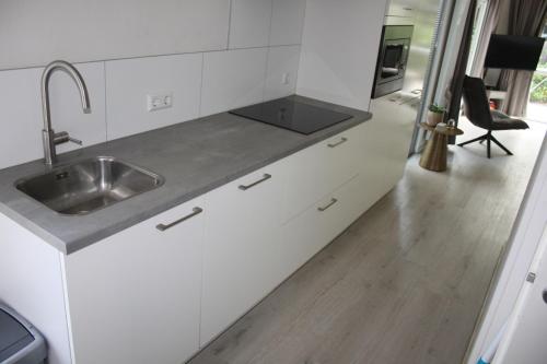 a kitchen with white cabinets and a sink at Rhederlaagse Meren in Lathum