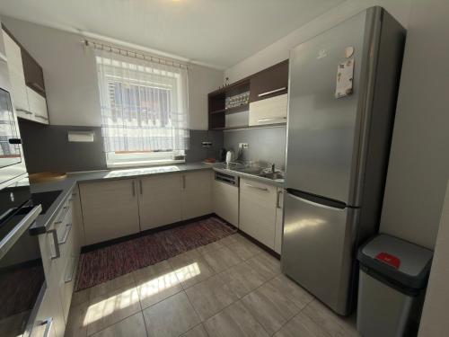 a kitchen with white cabinets and a stainless steel refrigerator at Chalupa GABO pre 15 osôb in Habovka