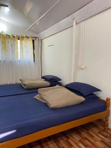 a bedroom with two beds with blue sheets and pillows at Anthony Stays Anjuna in Anjuna