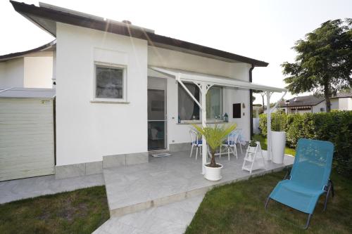 a white house with a patio and blue chairs at Galactic Sea in Comacchio