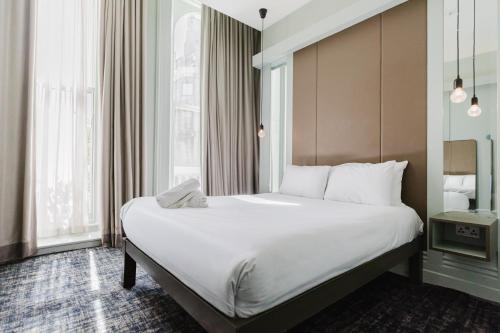 a hotel room with a large bed with white sheets at The Lancaster Hotel in London