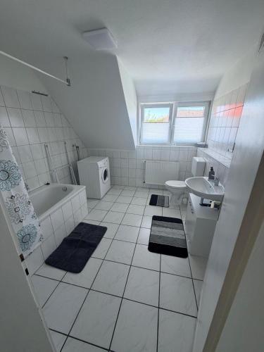 a white bathroom with a tub sink and a toilet at AlWi Apartment Wohnung 3 in Moringen