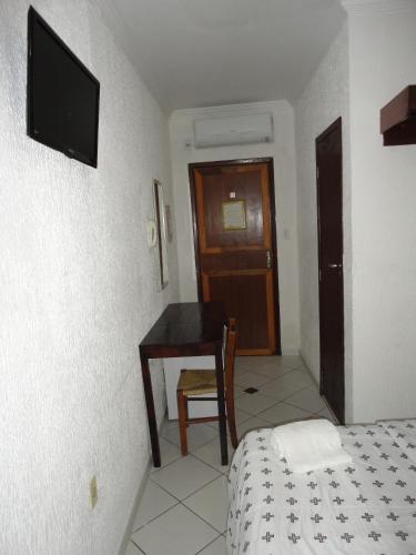 a bedroom with a table and a bed and a desk at Pousada Suítes Do Pelô in Salvador