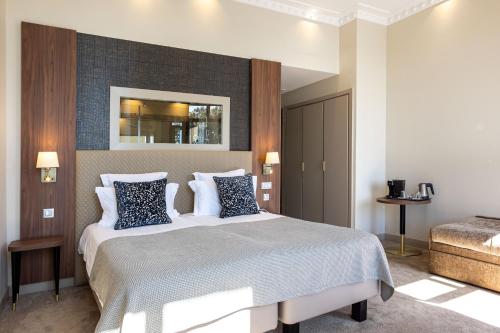 a bedroom with a large bed with blue and white pillows at Westminster Hotel & Spa Nice in Nice