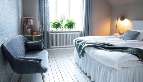 a bedroom with a bed and a chair and a window at Villa Tornhaga in Oskarström