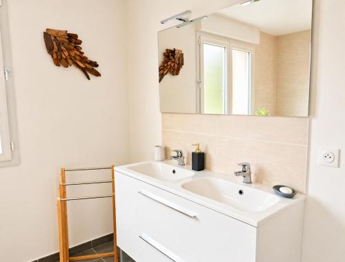 a bathroom with a white sink and a mirror at La Maison des Écumes in Crozon