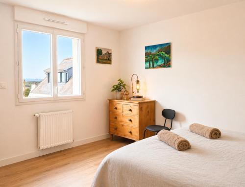 a bedroom with two beds and a dresser and a window at La Maison des Écumes in Crozon