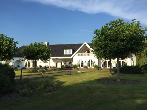 a large white house with a tree in the yard at Apartment Maasheuvel in Arcen