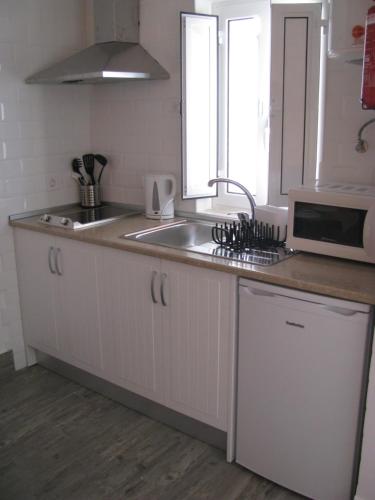 a kitchen with a sink and a microwave at Galega Guest House in Nazaré