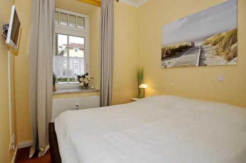 a bedroom with a white bed and a window at Dünenschloss Wohnung 1-05 in Kühlungsborn