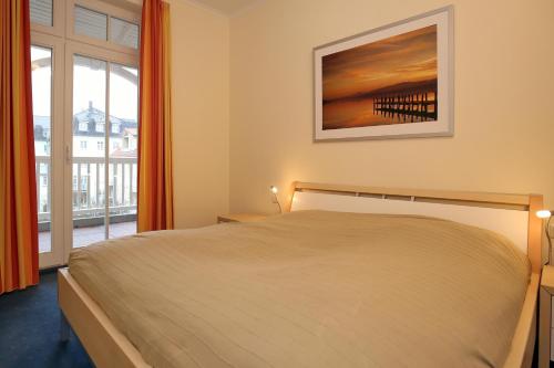 a bedroom with a bed and a large window at Dünenschloss Wohnung 1-22 in Kühlungsborn