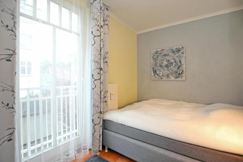 a bedroom with a bed and a large window at Dünenschloss Wohnung 2-11 in Kühlungsborn