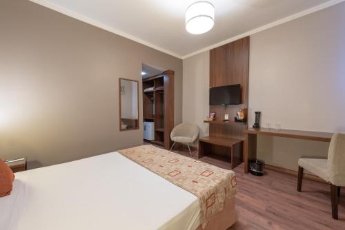 a hotel room with a bed and a desk at Class Hotel Varginha in Varginha