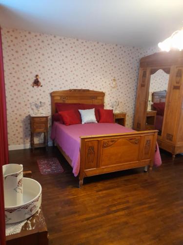 a bedroom with a wooden bed with red pillows at Chambres d'Hôtes et Table d'Hôtes- Valentine 44 in Sainte-Mère-Église