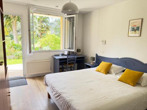 a bedroom with a bed and a desk and a window at Logis Hôtel La Demeure du Perron in Quettehou