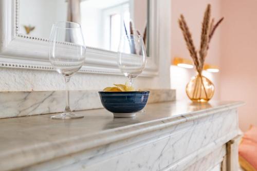 two wine glasses and a bowl on a mantle at Le Colibri in Foix