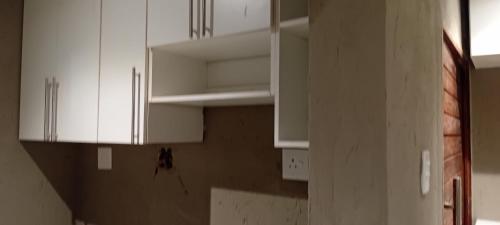 a kitchen with white cabinets in a room at Mkhuzewamanzi Accommodation in Mkuze