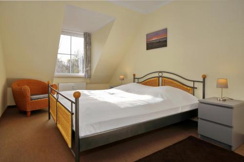 a bedroom with a bed and a chair and a window at Ostseewelle Wohnung 24 in Kühlungsborn
