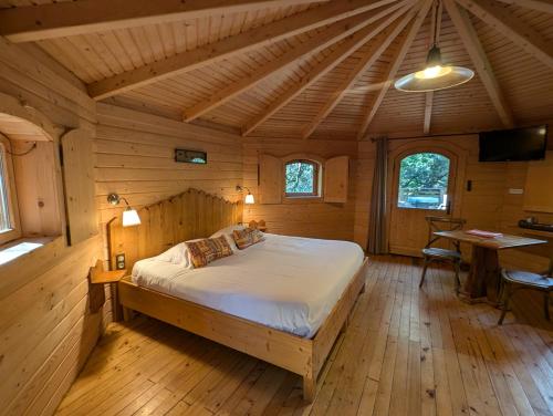 a bedroom with a bed in a wooden cabin at Les Cabanes Dans Les Bois Logis Hôtel in Villalier