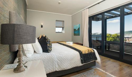 a bedroom with a bed with a lamp and a balcony at The Gallery 204 Luxury Apartment in Knysna