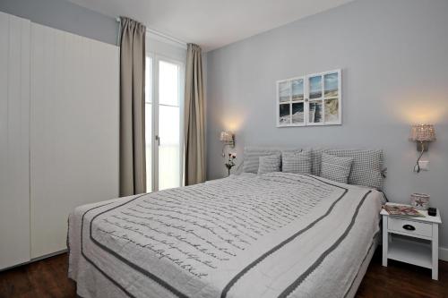 a white bedroom with a large bed and a window at Villa Seeadler Wohnung 07 in Börgerende-Rethwisch