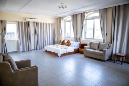 a bedroom with a bed and a couch and chairs at Ivory's Nest in Accra