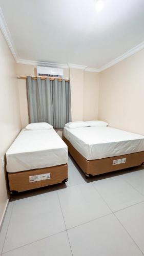 two twin beds in a room with white floors at Ed Flat Valdeliza Pio in Teresina