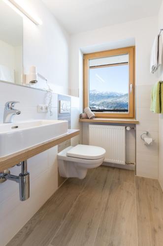 ein weißes Badezimmer mit Toilette und Fenster in der Unterkunft Hotel Kasimir in Riezlern
