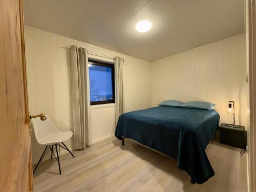 a bedroom with a bed and a chair and a window at Smørblomstvegen Apartment in Tromsø