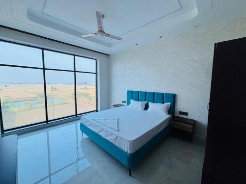 a bedroom with a blue bed and large windows at Hotel Picnic Garden in Patna