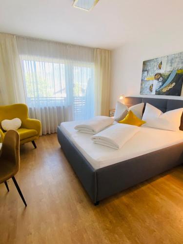 a bedroom with a large bed and a yellow chair at Hotel Garni Vinea Montis in Termeno