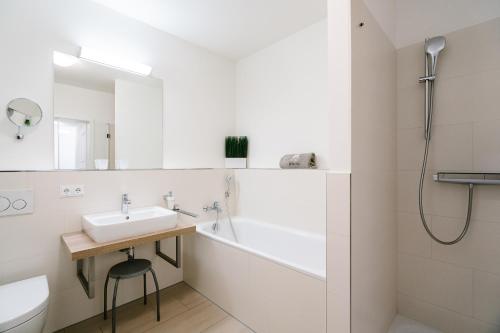 a white bathroom with a sink and a bath tub at Südkap B-07 in Pelzerhaken