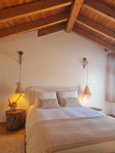 a bedroom with a large bed with wooden ceilings at Alba Odeceixe - casa clara in Odeceixe
