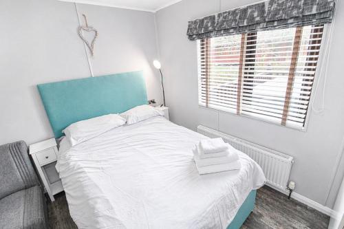 a bedroom with a bed with a blue headboard and a window at Grasmere 12, White Cross Bay, Windermere in Troutbeck Bridge