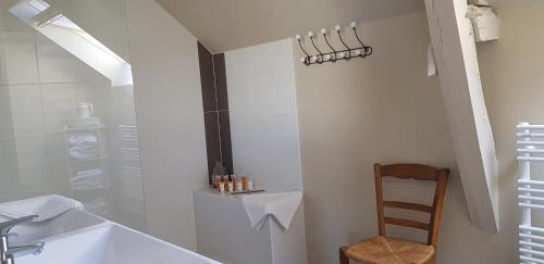 a bathroom with a shower and a sink and a chair at La Peuterne in Mouazé